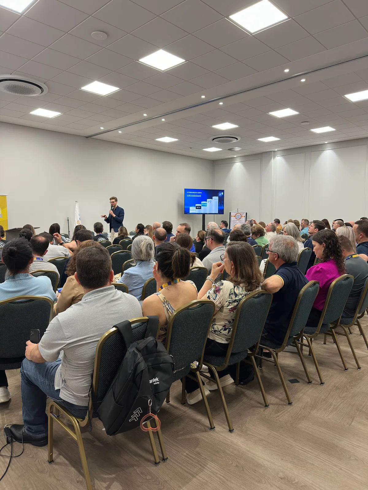 Salão cheio no evento do Senado JCI, com Ricardo Werlang ao fundo junto ao telão.
