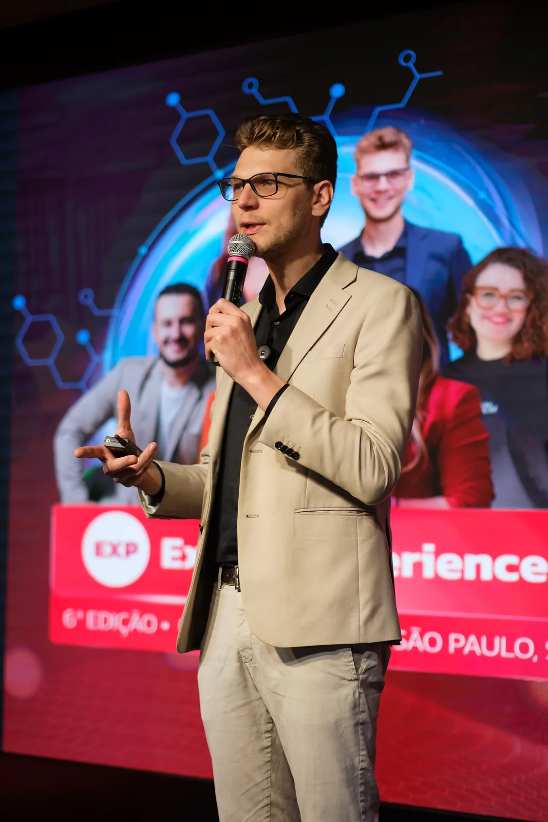 Ricardo Werlang no palco da 6ª edição do Expert Experience, em São Paulo, diante do painel do evento.