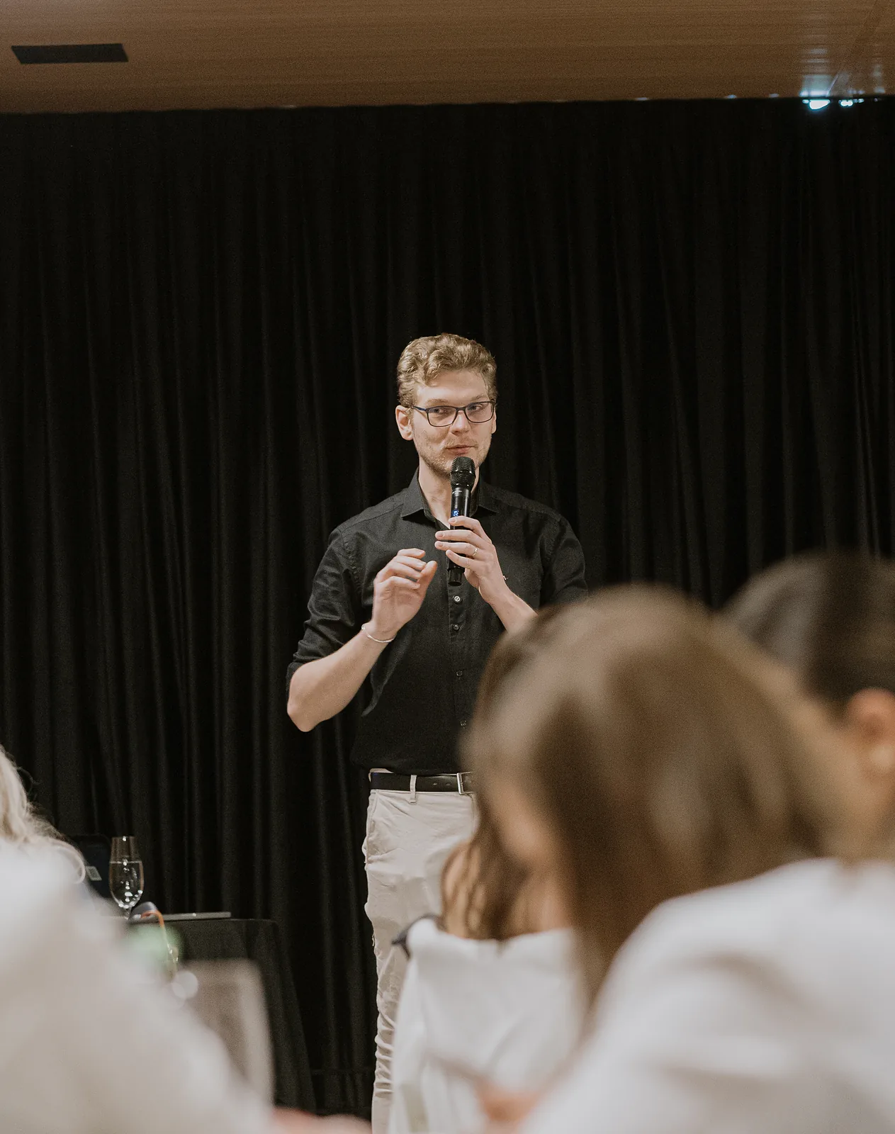 Ricardo Werlang falando ao microfone para a plateia do Evento Prospera, vista de trás do público.
